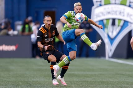 Jul 7, 2021; Seattle, Washington, USA; Seattle Sounders FC midfielder Kelyn Rowe (22) back heels a ball in front of Houston Dynamo defender Sam Junqua (29) during the first half at Lumen Field. Mandatory Credit: Jennifer Buchanan-USA TODAY Sports