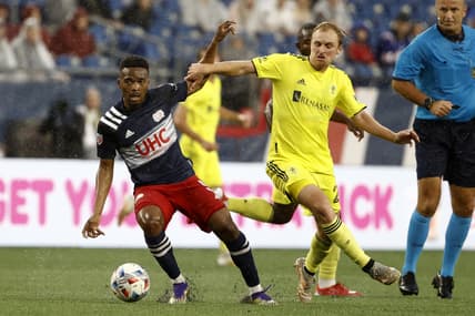 Aug 4, 2021; Foxborough, Massachusetts, USA; Nashville SC midfielder Matt LaGrassa (22) tries to hold up New England Revolution midfielder Wilfrid Kaptoum (5) during the first half at Gillette Stadium. Mandatory Credit: Winslow Townson-USA TODAY Sports