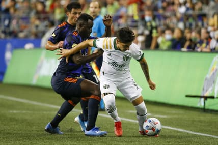 Aug 29, 2021; Seattle, Washington, USA; Portland Timbers defender Claudio Bravo (5) dribbles against Seattle Sounders FC defender Yeimar Gomez (28) during the first half at Lumen Field. Mandatory Credit: Joe Nicholson-USA TODAY Sports
