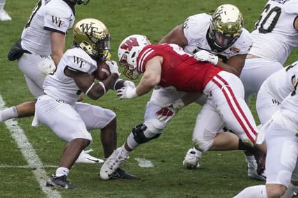 Dec 30, 2020; Charlotte, NC, USA; Wake Forest Demon Deacons running back Justice Ellison (14) is tackled for a loss of yardage by Wisconsin Badgers linebacker Leo Chenal (45) during second quarter action at Bank of America Stadium. Mandatory Credit: Jim Dedmon-USA TODAY Sports