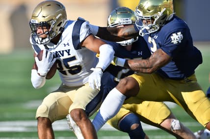 Nov 6, 2021; South Bend, Indiana, USA; Navy Midshipmen running back Carlinos Acie (25) is tackled by Notre Dame Fighting Irish safety DJ Brown (2) in the first quarter at Notre Dame Stadium. Mandatory Credit: Matt Cashore-USA TODAY Sports