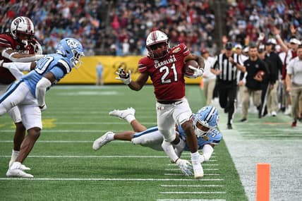 Dec 30, 2021; Charlotte, NC, USA; South Carolina Gamecocks running back Juju McDowell (21) runs for a touchdown as North Carolina Tar Heels linebacker Cedric Gray (33) defensive back Tony Grimes (20) defend in the second quarter during the 2021 Duke's Mayo Bowl at Bank of America Stadium. Mandatory Credit: Bob Donnan-USA TODAY Sports