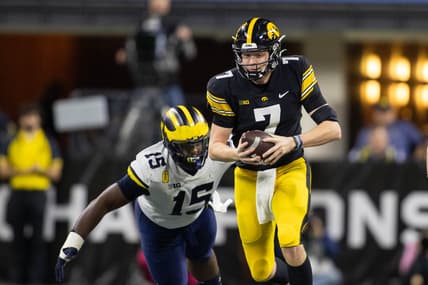Dec 4, 2021; Indianapolis, IN, USA;  Iowa Hawkeyes quarterback Spencer Petras (7) runs the ball while *Michigan Wolverines defensive lineman Christopher Hinton (15) defends in the second quarter at Lucas Oil Stadium. Mandatory Credit: Trevor Ruszkowski-USA TODAY Sports