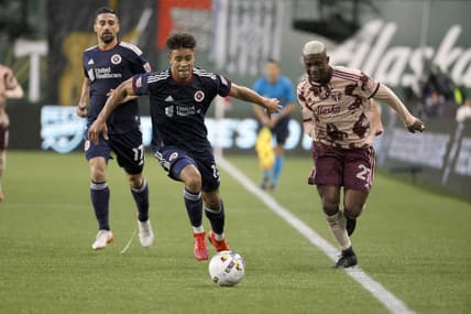 Feb 26, 2022; Portland, Oregon, USA; Portland Timbers forward Dairon Asprilla (27) dribbles the ball against New England Revolution defender Brandon Bye (15) during the first half at Providence Park. Mandatory Credit: Soobum Im-USA TODAY Sports