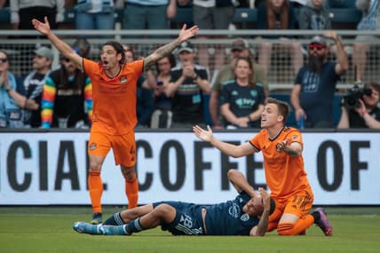 Mar 5, 2022; Kansas City, Kansas, USA; Houston Dynamo forward Corey Baird (11) and Houston Dynamo defender Zarek Valentin (4) react to a call after a collision with Sporting Kansas City defender Logan Ndenbe (18) at Children's Mercy Park. Mandatory Credit: William Purnell-USA TODAY Sports