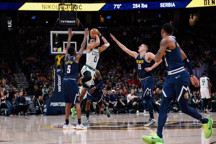 Mar 20, 2022; Denver, Colorado, USA; Boston Celtics forward Jayson Tatum (0) attempts a shot at the buzzer as Denver Nuggets forward Will Barton (5) and center Nikola Jokic (15) and guard Monte Morris (11) defend in the second quarter at Ball Arena. Mandatory Credit: Isaiah J. Downing-USA TODAY Sports