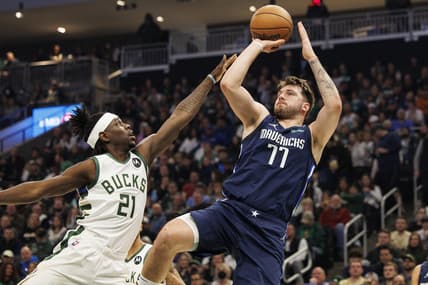 Apr 3, 2022; Milwaukee, Wisconsin, USA;  Dallas Mavericks guard Luka Doncic (77) shoots against Milwaukee Bucks guard Jrue Holiday (21) during the first quarter at Fiserv Forum. Mandatory Credit: Jeff Hanisch-USA TODAY Sports