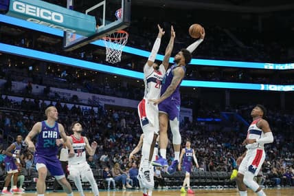 Apr 10, 2022; Charlotte, North Carolina, USA; Charlotte Hornets forward Miles Bridges (0) goes for the dunk defended by Washington Wizards center Daniel Gafford (21) during the second half at Spectrum Center. Mandatory Credit: Jim Dedmon-USA TODAY Sports