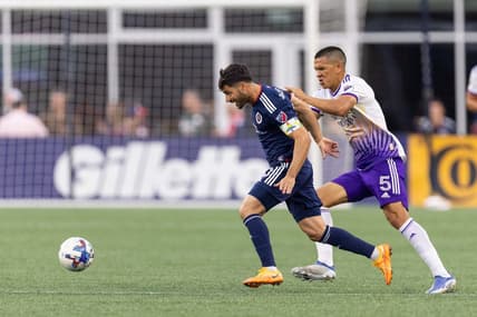 Jun 15, 2022; Foxborough, Massachusetts, USA; Orlando City SC midfielder Cesar Araujo (5) defends New England Revolution midfielder Carles Gil (10) during the first half at Gillette Stadium. Mandatory Credit: Paul Rutherford-USA TODAY Sports