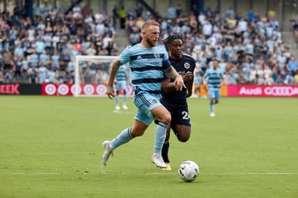 Jun 12, 2022; Kansas City, Kansas, USA; Sporting Kansas City forward Johnny Russell (7) running with the ball with New England Revolution forward DeJuan Jones (24) defending at Children's Mercy Park. Mandatory Credit: Gary Rohman-USA TODAY Sports