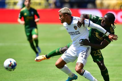 Jun 18, 2022; Carson, California, USA; Los Angeles Galaxy defender Julian Araujo (2) plays for the ball against Portland Timbers forward Yimmi Chara (23) during the first half at Dignity Health Sports Park. Mandatory Credit: Gary A. Vasquez-USA TODAY Sports