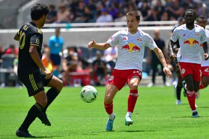 Jun 26, 2022; Los Angeles, California, USA; New York Red Bulls defender John Tolkin (47) plays for the ball against Los Angeles FC forward Carlos Vela (10) during the second half at Banc of California Stadium. Mandatory Credit: Gary A. Vasquez-USA TODAY Sports
