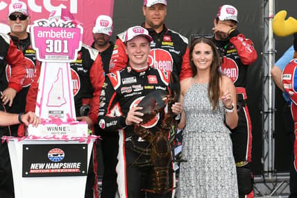 Jul 17, 2022; Loudon, New Hampshire, USA; NASCAR Cup Series driver Christopher Bell (20) and wife Morgan Kemenah celebrate on victory lane with Loudon the lobster after the Ambetter 301 at New Hampshire Motor Speedway. Mandatory Credit: Eric Canha-USA TODAY Sports