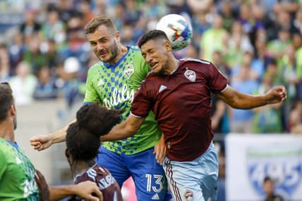 Jul 23, 2022; Seattle, Washington, USA; Seattle Sounders FC forward Jordan Morris (13) jumps for a corner kick against Colorado Rapids midfielder Bryan Acosta (21) during the first half at Lumen Field. Mandatory Credit: Joe Nicholson-USA TODAY Sports