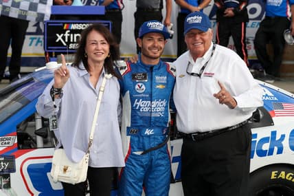 Aug 20, 2022; Watkins Glen, New York, USA; NASCAR Xfinity Series driver Kyle Larson celebrates with owner Rick Hendrick (right) and his wife Linda Hendrick (left) in victory lane after winning the Sunoco Go Rewards 200 at Watkins Glen International. Mandatory Credit: Matthew OHaren-USA TODAY Sports