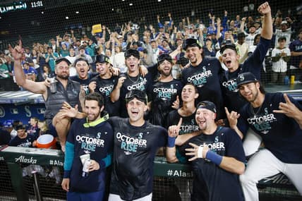 Sep 30, 2022; Seattle, Washington, USA; Seattle Mariners players and staff, including relief pitcher Matthew Boyd (first row, second from left) and catcher Cal Raleigh (first row second from right) celebrate in the dugout following a 2-1 victory against the Oakland Athletics to clinch a wild card playoff berth at T-Mobile Park. Mandatory Credit: Joe Nicholson-USA TODAY Sports