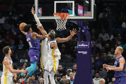 Oct 29, 2022; Charlotte, North Carolina, USA; Charlotte Hornets guard Dennis Smith Jr. (8) goes up for a shot against Golden State Warriors center Kevon Looney (5) and forward Jonathan Kuminga (00) during the second quarter at Spectrum Center. Mandatory Credit: Jim Dedmon-USA TODAY Sports