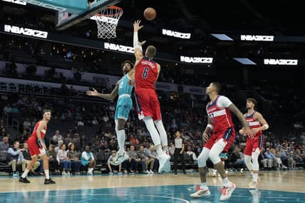 Nov 7, 2022; Charlotte, North Carolina, USA; Charlotte Hornets guard Kelly Oubre Jr. (12) shoots defended by Washington Wizards center Kristaps Porzingis (6) during the first quarter at Spectrum Center. Mandatory Credit: Jim Dedmon-USA TODAY Sports