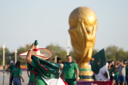 Nov 22, 2022; Doha, Qatar; A Mexico fan wearing a sombrero walks past a World Cup trophy replica outside the stadium before the match against Poland during a group stage match at the 2022 World Cup at Ras Abu Aboud Stadium. Mandatory Credit: Danielle Parhizkaran-USA TODAY Sports