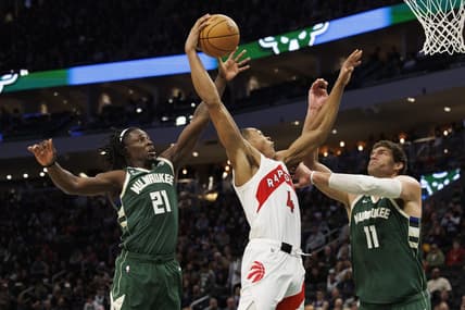 Jan 17, 2023; Milwaukee, Wisconsin, USA;  Toronto Raptors forward Scottie Barnes (4) shoots between Milwaukee Bucks guard Jrue Holiday (21) and center Brook Lopez (11) during the third quarter at Fiserv Forum. Mandatory Credit: Jeff Hanisch-USA TODAY Sports