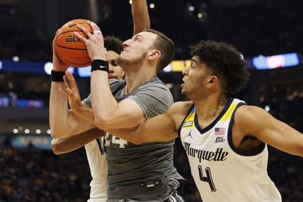 Feb 15, 2023; Milwaukee, Wisconsin, USA;  Xavier Musketeers forward Jack Nunge (24) drives for the basket between Marquette Golden Eagles forward Oso Ighodaro (13) and guard Stevie Mitchell (4) during the first half at Fiserv Forum. Mandatory Credit: Jeff Hanisch-USA TODAY Sports