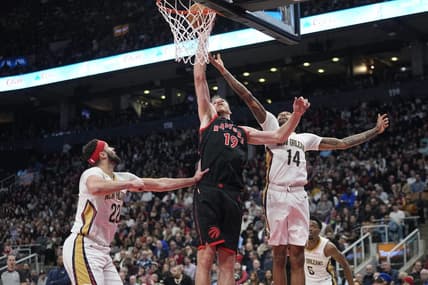 Feb 23, 2023; Toronto, Ontario, CAN; Toronto Raptors center Jakob Poeltl (19) tips in a ball against New Orleans Pelicans forward Brandon Ingram (14) and  forward Larry Nance Jr. (22) during the first half at Scotiabank Arena. Mandatory Credit: John E. Sokolowski-USA TODAY Sports