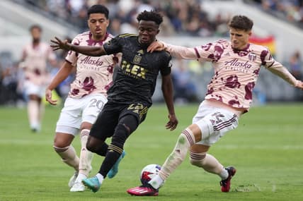 Mar 4, 2023; Los Angeles, California, USA; Los Angeles FC forward Kwadwo Opoku (22) is challenged from behind by Portland Timbers defender Justin Rasmussen (14) during the second half at BMO Stadium. Mandatory Credit: Jason Parkhurst-USA TODAY Sports