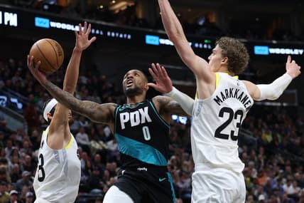 Mar 22, 2023; Salt Lake City, Utah, USA; Portland Trail Blazers guard Damian Lillard (0) drives between Utah Jazz guard Johnny Juzang (33) and forward Lauri Markkanen (23) in the second quarter at Vivint Arena. Mandatory Credit: Rob Gray-USA TODAY Sports