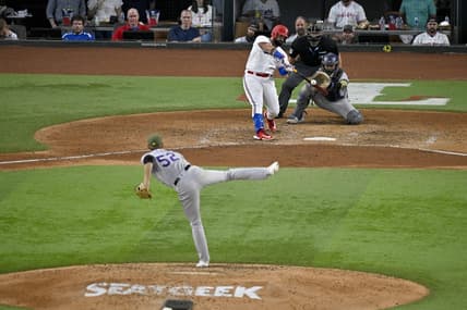May 20, 2023; Arlington, Texas, USA; Texas Rangers catcher Sandy Leon (12) bats against Colorado Rockies relief pitcher Daniel Bard (52) during the game at Globe Life Field. Mandatory Credit: Jerome Miron-USA TODAY Sports