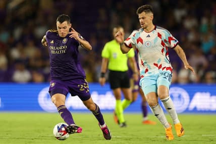 Jul 1, 2023; Orlando, Florida, USA;  Orlando City SC defender Kyle Smith (24) controls the ball from Chicago Fire FC midfielder Gaston Gimenez (30) in the second half at Exploria Stadium. Mandatory Credit: Nathan Ray Seebeck-USA TODAY Sports