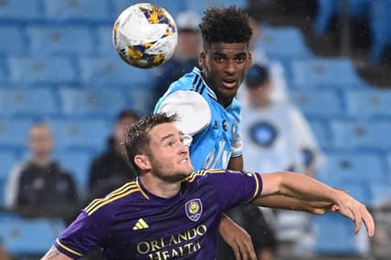 Aug 30, 2023; Charlotte, North Carolina, USA; Charlotte FC defender Adilson Malanda (29) heads the ball as Orlando City forward Duncan McGuire (13) defends in the first half at Bank of America Stadium. Mandatory Credit: Bob Donnan-USA TODAY Sports