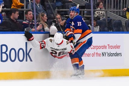 Oct 26, 2023; Elmont, New York, USA; New York Islanders right wing Cal Clutterbuck (15) checks Ottawa Senators defenseman Erik Brannstrom (26) into the boards during the second period at UBS Arena. Mandatory Credit: Dennis Schneidler-USA TODAY Sports
