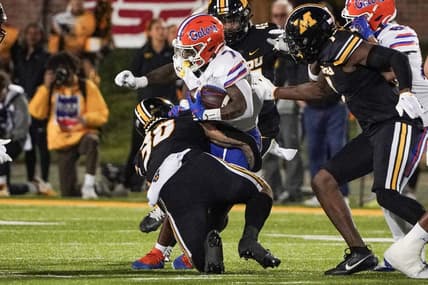 Nov 18, 2023; Columbia, Missouri, USA; Florida Gators running back Trevor Etienne (7) runs the ball as Missouri Tigers linebacker Chuck Hicks (30) makes the tackle during the first half at Faurot Field at Memorial Stadium. Mandatory Credit: Denny Medley-USA TODAY Sports