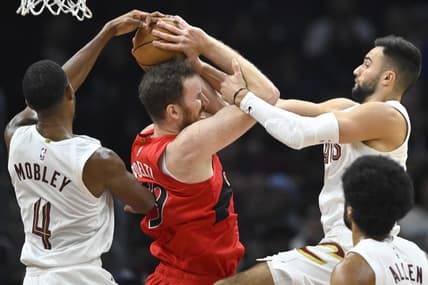Nov 26, 2023; Cleveland, Ohio, USA; Cleveland Cavaliers forward Evan Mobley (4) and guard Max Strus (1) defend Toronto Raptors center Jakob Poeltl (19) in the second quarter at Rocket Mortgage FieldHouse. Mandatory Credit: David Richard-USA TODAY Sports