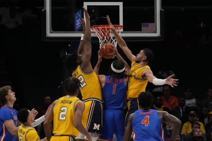 Dec 19, 2023; Charlotte, North Carolina, USA; Florida Gators guard Walter Clayton Jr. (1) is sandwiched at the basket by Michigan Wolverines forward Tarris Reed Jr. (32) and forward Olivier Nkamhoua (13) during the first half at Spectrum Center. Mandatory Credit: Jim Dedmon-USA TODAY Sports