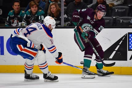 Dec 31, 2023; Anaheim, California, USA; Anaheim Ducks left wing Brock McGinn (26) passes the puck against Edmonton Oilers defenseman Mattias Ekholm (14) during the second period at Honda Center. Mandatory Credit: Gary A. Vasquez-USA TODAY Sports