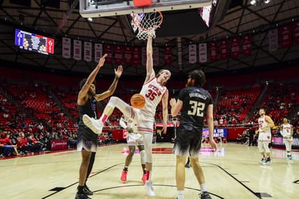 Dec 31, 2023; Salt Lake City, Utah, USA; Utah Utes center Branden Carlson (35) hangs onto the basket after dunking over Washington Huskies forward Wilhelm Breidenbach (32) during the second half at the the Jon M. Huntsman Center. Mandatory Credit: Christopher Creveling-USA TODAY Sports