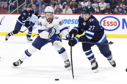 Jan 2, 2024; Winnipeg, Manitoba, CAN; Winnipeg Jets left wing Nikolaj Ehlers (27) is stick checked by Tampa Bay Lightning center Tyler Motte (64) in the first period at Canada Life Centre. Mandatory Credit: James Carey Lauder-USA TODAY Sports