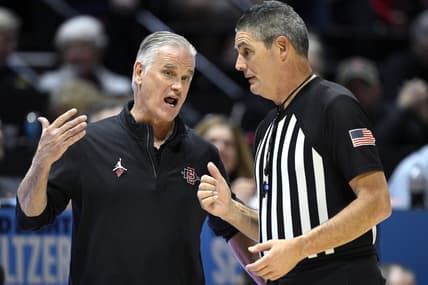 Jan 6, 2024; San Diego, California, USA; San Diego State Aztecs head coach Brian Dutcher (left) speaks with referee Michael Reed during the second half against the UNLV Rebels at Viejas Arena. Mandatory Credit: Orlando Ramirez-USA TODAY Sports