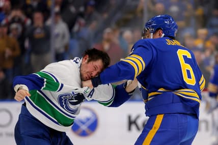 Jan 13, 2024; Buffalo, New York, USA;  Buffalo Sabres defenseman Erik Johnson (6) and Vancouver Canucks center J.T. Miller (9) fight during the second period at KeyBank Center. Mandatory Credit: Timothy T. Ludwig-USA TODAY Sports