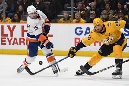 Jan 13, 2024; Nashville, Tennessee, USA; New York Islanders right wing Cal Clutterbuck (15) shoots the puck against Nashville Predators center Ryan O'Reilly (90) during the second period at Bridgestone Arena. Mandatory Credit: Christopher Hanewinckel-USA TODAY Sports