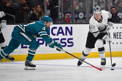 Jan 22, 2024; Los Angeles, California, USA; Los Angeles Kings defenseman Brandt Clarke (92) moves the puck against San Jose Sharks center Tomas Hertl (48) during the second period at Crypto.com Arena. Mandatory Credit: Gary A. Vasquez-USA TODAY Sports