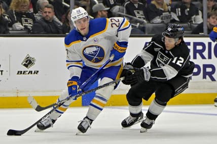 Jan 24, 2024; Los Angeles, California, USA; Buffalo Sabres right wing Jack Quinn (22) handles the puck as he is defended by Los Angeles Kings left wing Trevor Moore (12) in the second period at Crypto.com Arena. Mandatory Credit: Jayne Kamin-Oncea-USA TODAY Sports