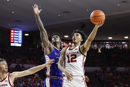 Feb 17, 2024; Norman, Oklahoma, USA; Oklahoma Sooners guard Milos Uzan (12) goes up for a basket beside Kansas Jayhawks forward K.J. Adams Jr. (24) during the second half at Lloyd Noble Center. Mandatory Credit: Alonzo Adams-USA TODAY Sports
