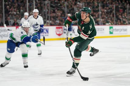 Feb 19, 2024; Saint Paul, Minnesota, USA; Minnesota Wild center Joel Eriksson Ek (14) shoots as Vancouver Canucks right wing Conor Garland (8) defends in the second period at Xcel Energy Center. Mandatory Credit: Matt Blewett-USA TODAY Sports