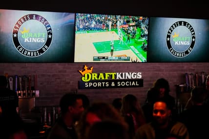 Sports are shown on TVs behind a bar as guests enjoy the grand opening of DraftKings Sports & Social in Ohio.
