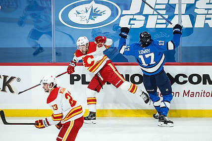 Feb 1, 2021; Winnipeg, Manitoba, CAN;  Calgary Flames defenseman Nikita Nesterov (89) and Winnipeg Jets forward Adam Lowry (17) react to a collision during the first period at Bell MTS Place. Mandatory Credit: Terrence Lee-USA TODAY Sports