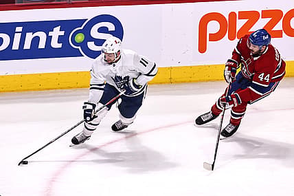 Apr 12, 2021; Montreal, Quebec, CAN; Toronto Maple Leafs left wing Zach Hyman (11) plays the puck against Montreal Canadiens defenseman Joel Edmundson (44) during the first period at Bell Centre. Mandatory Credit: Jean-Yves Ahern-USA TODAY Sports