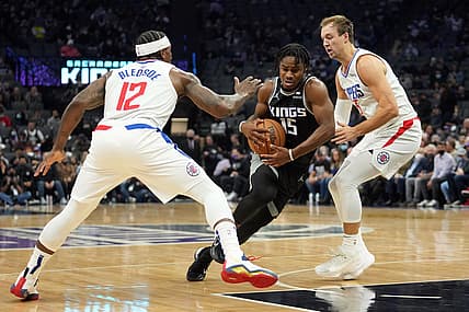 Dec 4, 2021; Sacramento, California, USA; Sacramento Kings guard Davion Mitchell (15) drives between LA Clippers guards Eric Bledsoe (12) and Luke Kennard (5) during the first quarter at Golden 1 Center. Mandatory Credit: Darren Yamashita-USA TODAY Sports