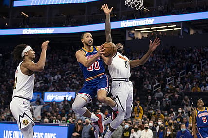 Dec 28, 2021; San Francisco, California, USA; Golden State Warriors guard Stephen Curry (30) is fouled as he drives to the basket between Denver Nuggets forward Zeke Nnaji (22) and guard Davon Reed (9) during the fourth quarter at Chase Center. Mandatory Credit: D. Ross Cameron-USA TODAY Sports